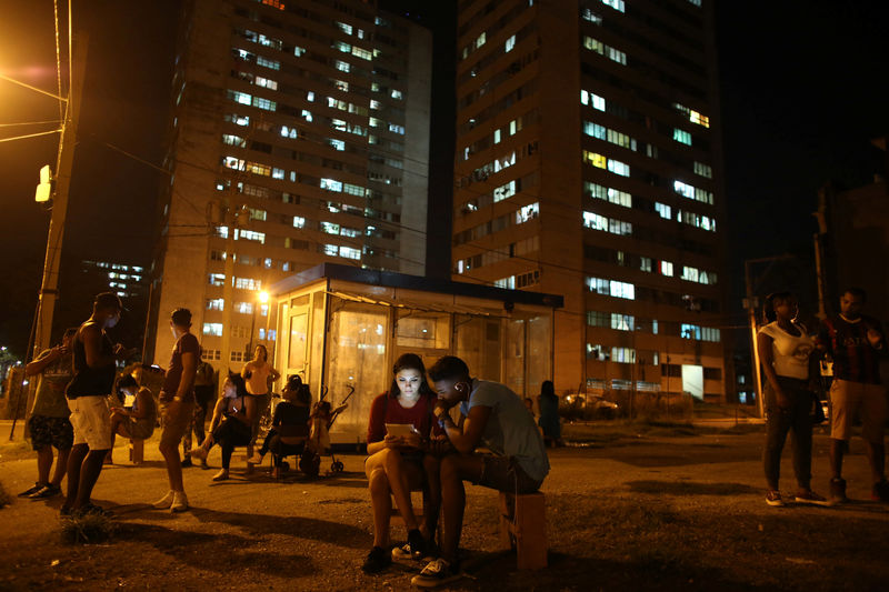 © Reuters. Gutierrez and Valdez use mobile phones to connect to the internet at a hotspot in downtown Havana