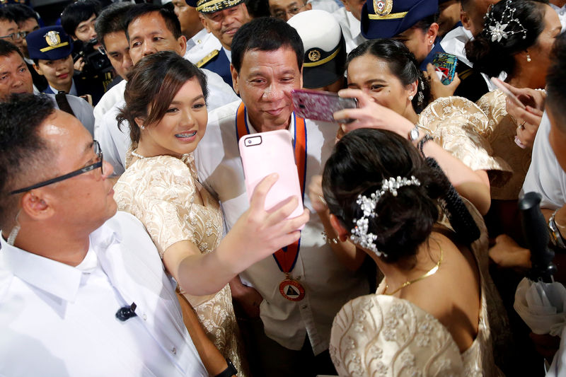 © Reuters. Philippines President Rodrigo Duterte has his pictures taken with women as they attend the ceremony marking the anniversary of the Philippines Coast Guard in Manila