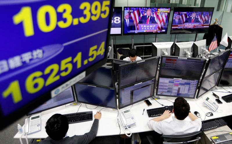 © Reuters. Employees of a foreign exchange trading company work near monitors showing U.S. President elect Donald Trump speaking on TV news, and the Japanese yen's exchange rate against the U.S. dollar and Japan's Nikkei average in Tokyo