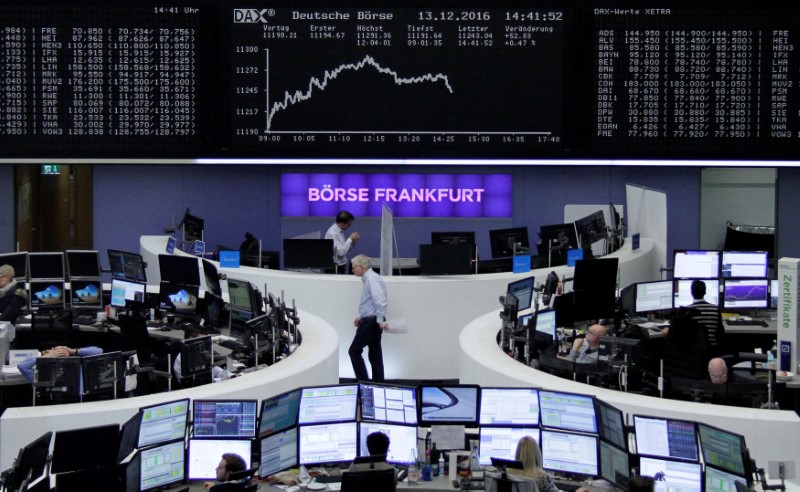 © Reuters. Traders work at their desks in front of the German share price index, DAX board, in Frankfurt