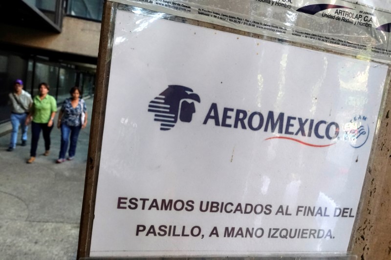 © Reuters. People walk past a sign with the logo of Aeromexico at their office in Caracas
