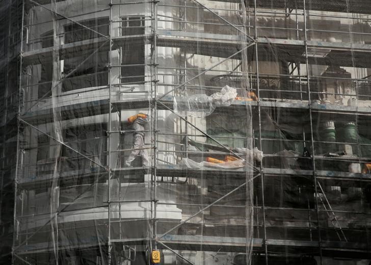 © Reuters. A construction worker carries a sack on a scaffold in Madrid