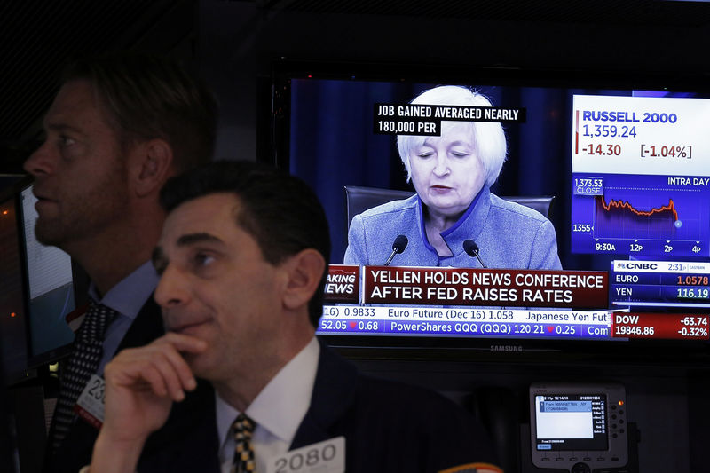 © Reuters. A trader works on the floor of the New York Stock Exchange as a television screen displays coverage of U.S. Federal Reserve Chairman Janet Yellen shortly after the announcement that the U.S. Federal Reserve will hike interest rates, in New York