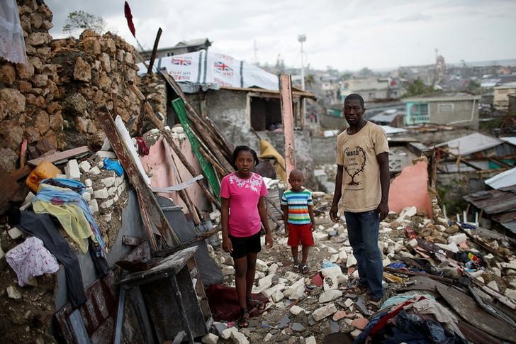 © Reuters. Família em meio a destroços após passagem do furacão Matthew no Haiti