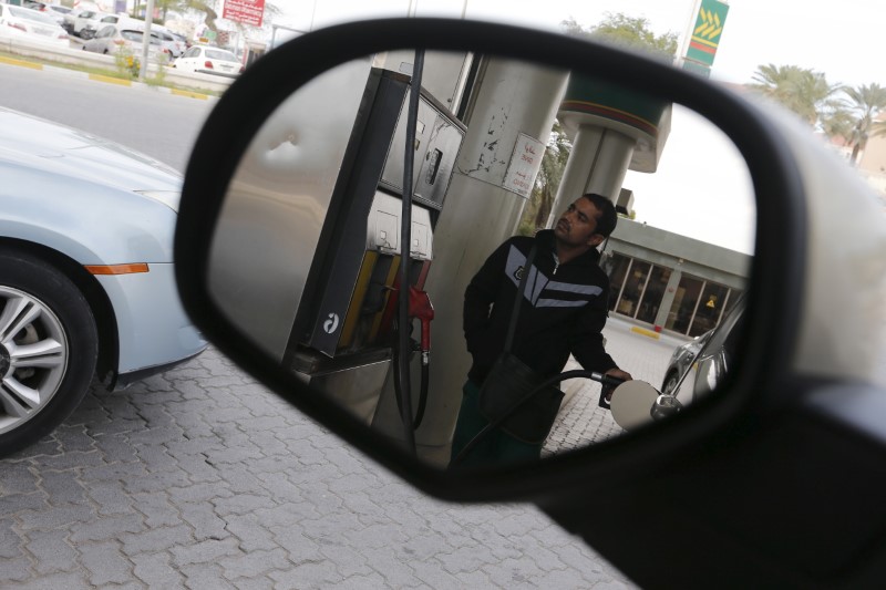 © Reuters. A fuel pump assistant fills cars with petrol at Budaiya Fueling Station west of Manama, Bahrain