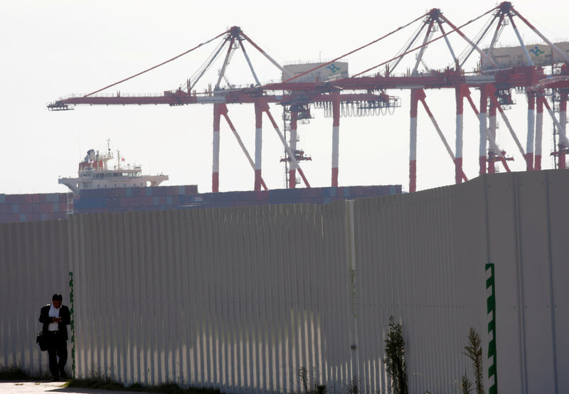 © Reuters. A man is seen in front of cranes at an industrial port in Tokyo