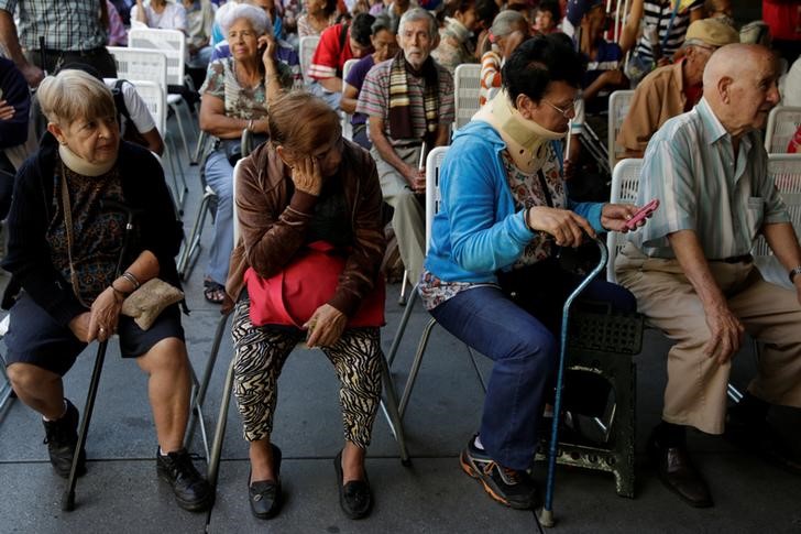 © Reuters. Pessoas fazem fila para depositar suas notas de 100 bolívares em Caracas