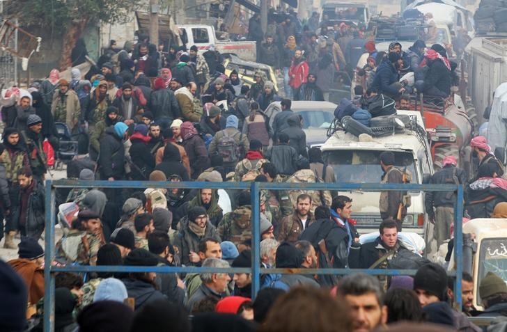 © Reuters. Rebel fighters and civilians gather as they wait to be evacuated from a rebel-held sector of eastern Aleppo