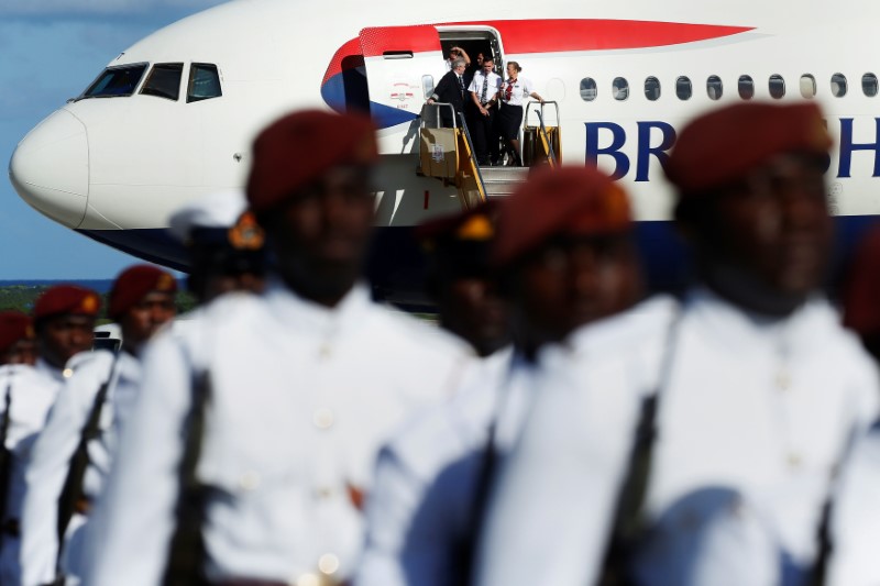 © Reuters. A British Airways flight crew watches as Prince Harry inspects members of Antigua's military as he arrives at the airport for an official visit in Antigua