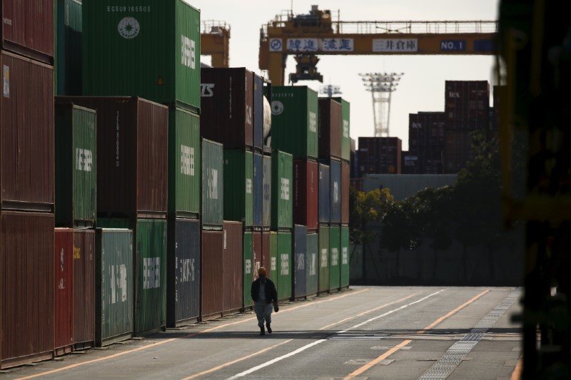 © Reuters. A worker walks between shipping containers at a port in Tokyo