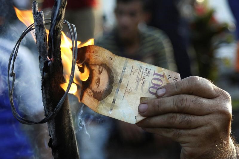 © Reuters. Homem queima nota de 100 bolívares em protesto em El Pinal