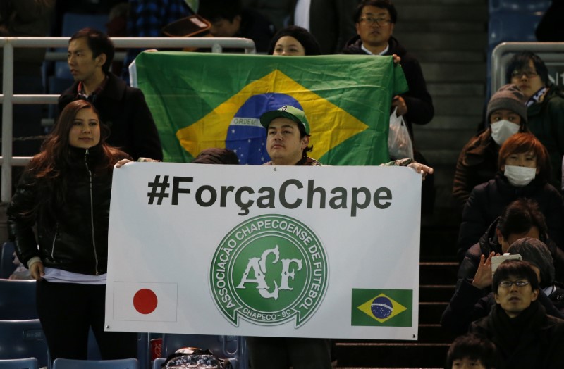 © Reuters. A fan holds a banner for the victims of the Colombia plane crash containing the Chapecoense players and staff before the match