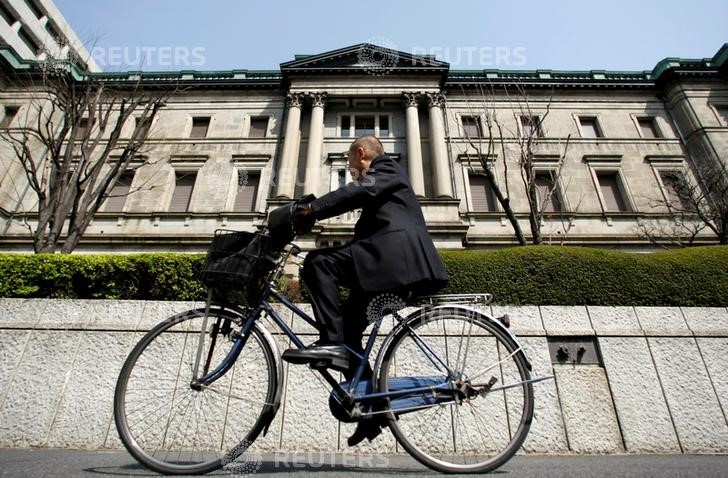 © Reuters. A man rides a bicycle past the BOJ building in Tokyo