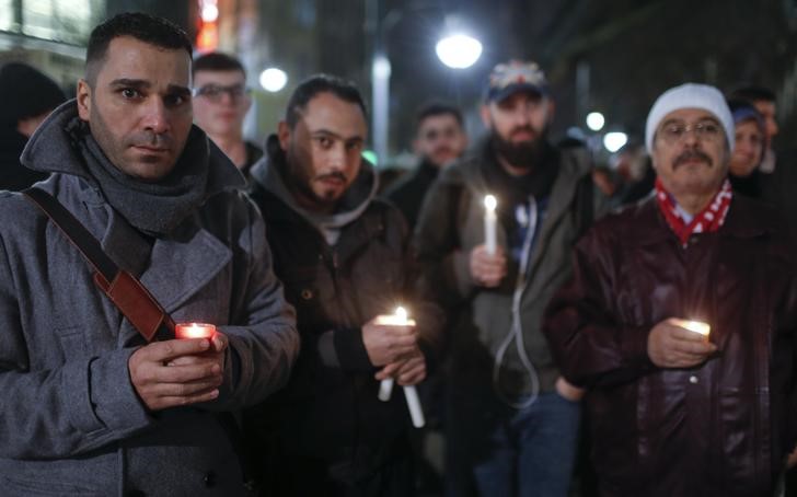 © Reuters. Refugiados seguram velas em homenagem às vítimas do caminhão que avançou contra uma multidão em um feira de Natal em Berlim