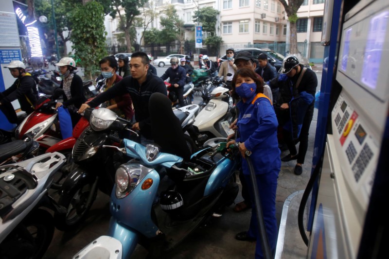 © Reuters. An employee pumps petrol for clients at a petrol station in Hanoi