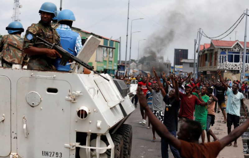 © Reuters. Residents chant slogans against Congolese President Joseph Kabila as peacekeepers MONUSCO patrol during demonstrations in the streets of the DRC capital Kinshasa