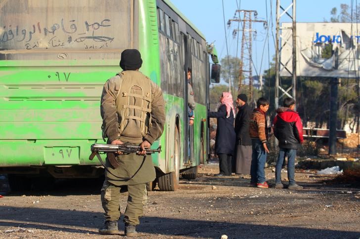 © Reuters. Rebelde perto de ônibus para retirada de moradores de vilas xiitas na Síria