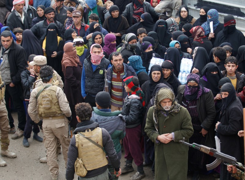 © Reuters. Displaced Iraqis from Mosul, who are fleeing from Islamic State militants, gather to receive aid in the east of Mosul