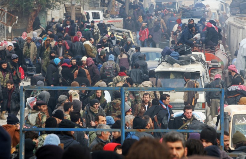 © Reuters. Rebel fighters and civilians gather as they wait to be evacuated from a rebel-held sector of eastern Aleppo