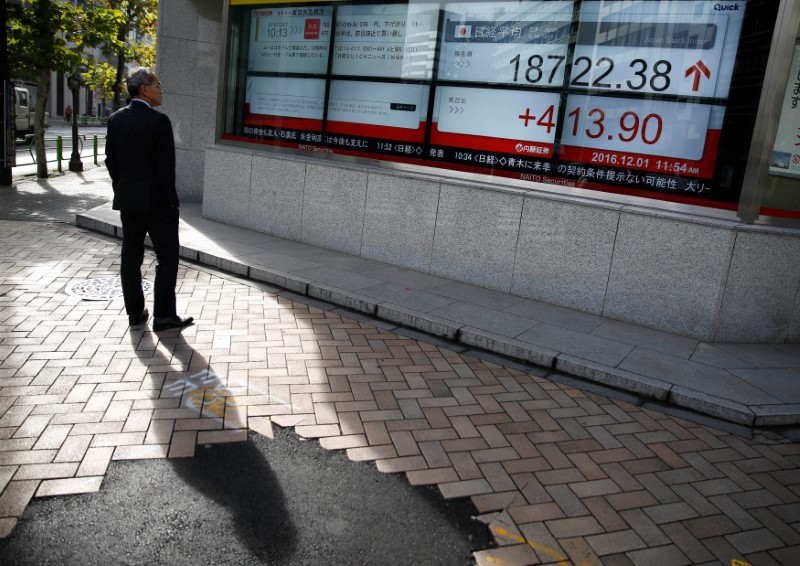 © Reuters. A man looks at an electronic board showing Japan's Nikkei average outside a brokerage in Tokyo