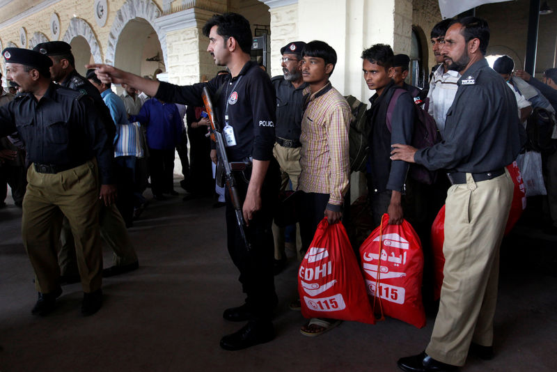 © Reuters. Fishermen from India hold handouts as they are guided by policemen, after they were released from a prison, at Cantonment railway station in Karachi