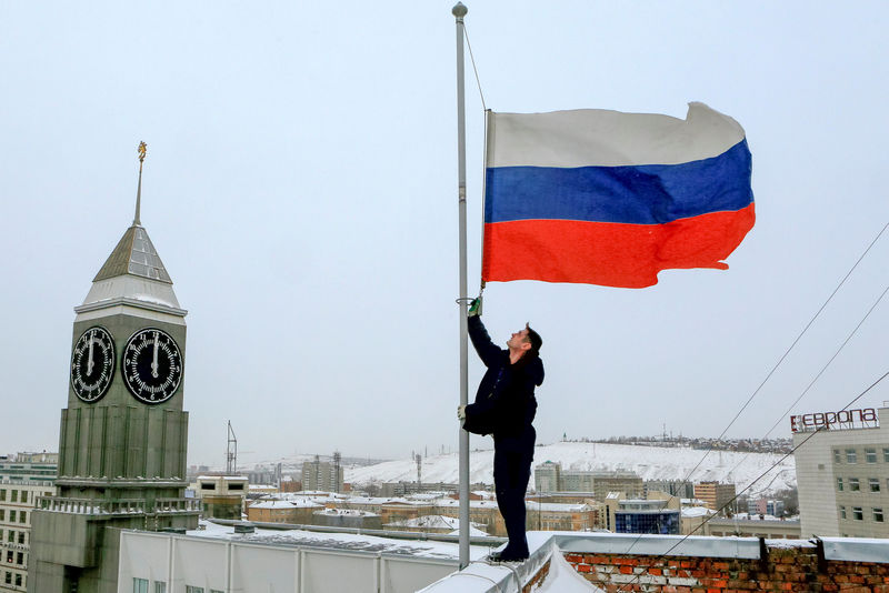 © Reuters. Funcionário coloca bandeira nacional russa a meio-mastro em Krasnoyarsk, Rússia, após acidente com avião no Mar Negro