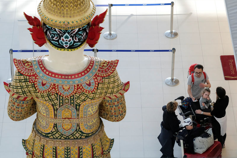 © Reuters. Turistas ao lado de estátua no aeroporto de Bangcoc