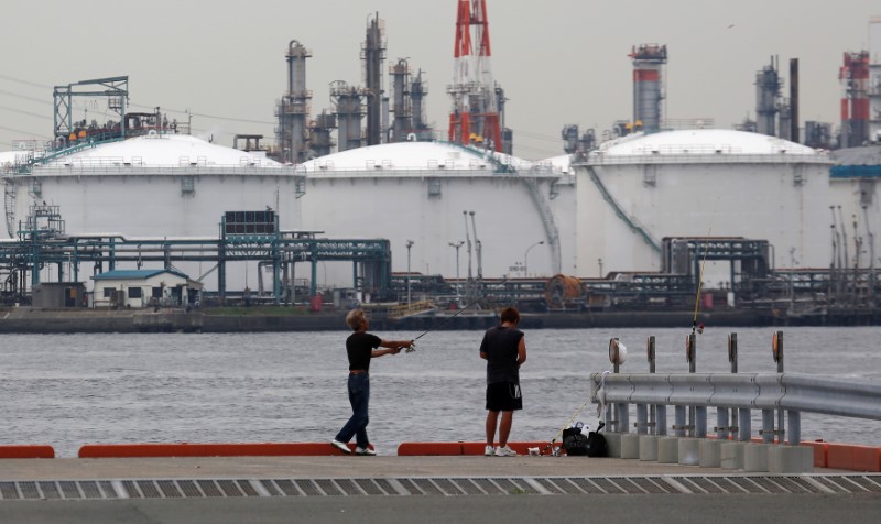 © Reuters. Men fish near an oil refinery in Kawasaki