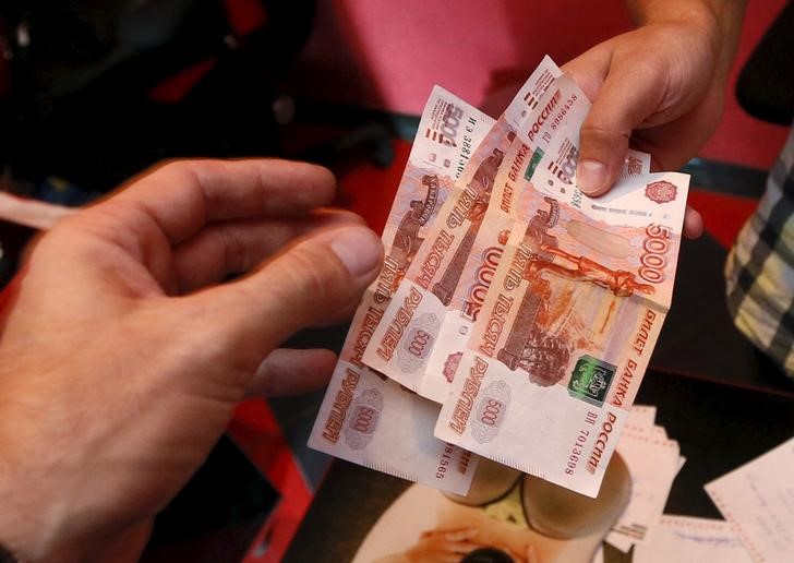 © Reuters. Служащий автосервиса берет у клиента рублевые банкноты