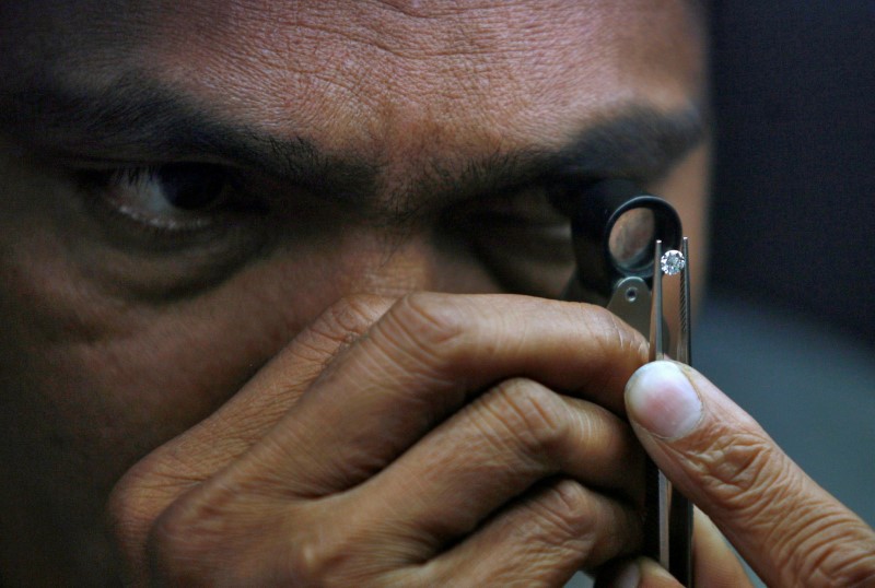 © Reuters. FILE PHOTO: A supervisor checks the shape of a polished diamond inside the diamond processing unit at Surat, in the western Indian state of Gujarat