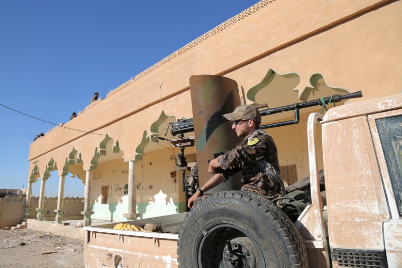 © Reuters. A Syrian Democratic Forces (SDF) fighter sits on the back of a pick-up truck with a weapon installed on it, in Tal Samin village, north of Raqqa city