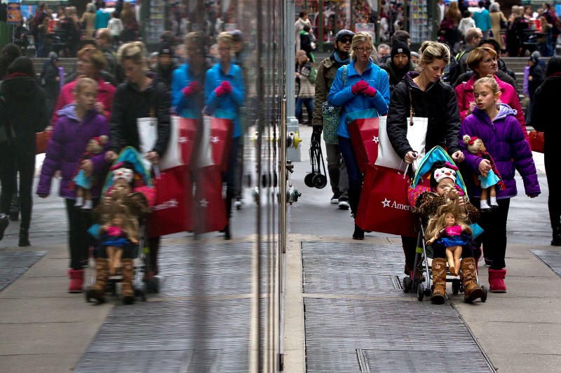 © Reuters. Shoppers are reflected in a window as they walk though Times Square in New York