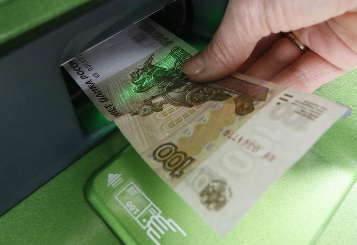 © Reuters. Женщина вносит 100-рублевую купюру в банкомат Сбербанка