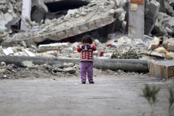 © Reuters. Девочка играет рядом с развалинами дома в северном районе Алеппо