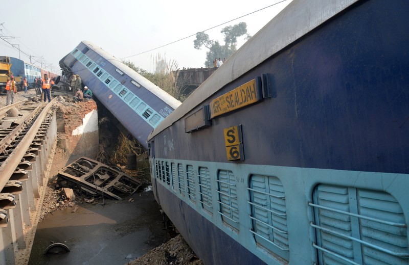 © Reuters. Rescuers and railway officials stand next to derailed coaches of a passenger train near Kanpur