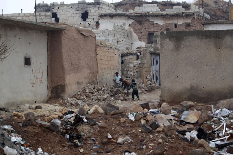 © Reuters. Children play near rubble of damaged buildings in al-Rai town