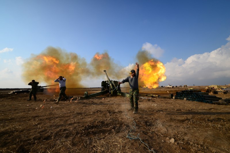 © Reuters. Membros das Forças de Mobilização Popular do Iraque disparam na direção de posições do Estado Islâmico a oeste de Mosul