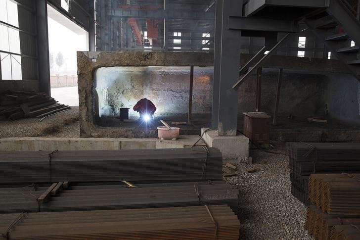 © Reuters. Trabalhador em meio a barras de aço em depósito da Baifeng Iron and Steel Corporation em Tangshan, na China