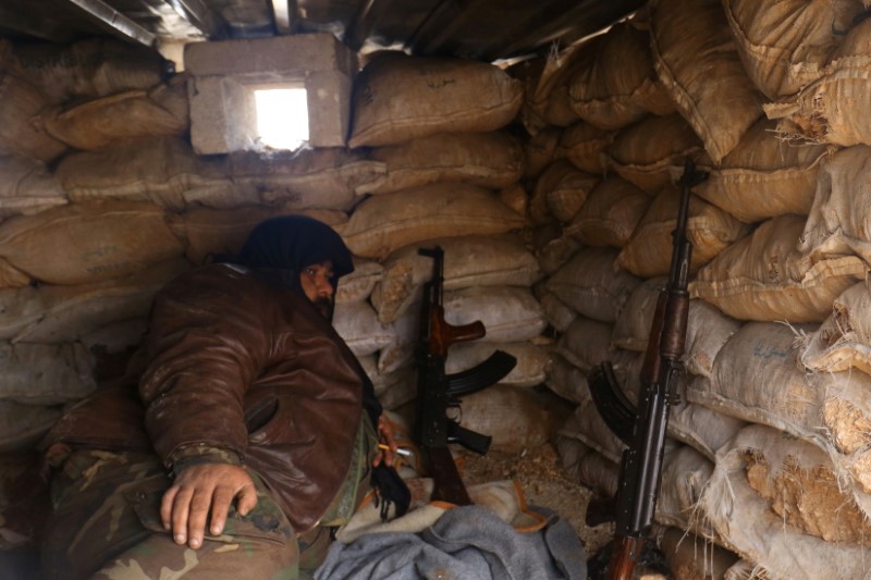 © Reuters. Combatente rebelde descansa com suas armas atrás de sacos de areia em área controlada por insurgentes na província de Aleppo