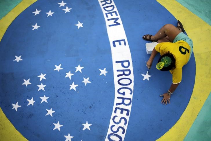 © Reuters. Mulher pinta a bandeira do Brasil em uma rua