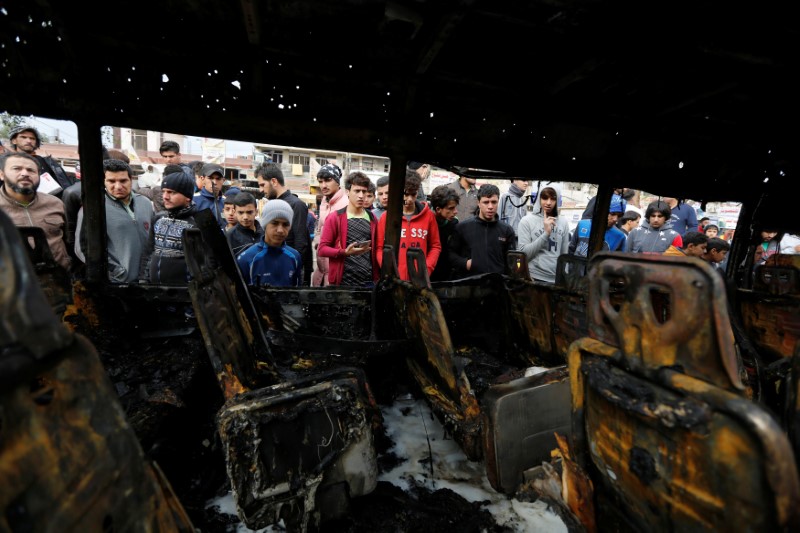 © Reuters. Pessoas observam veículo destruído em local de explosão em Sadr City, em Bagdá