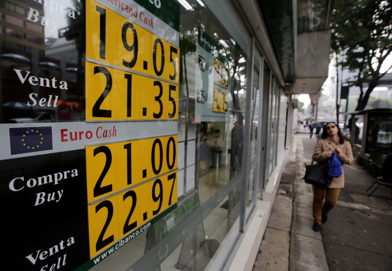 © Reuters. A woman walks past a board displaying the exchange rate for Mexican peso against the U.S. dollar and the Euro at a bank in Mexico City