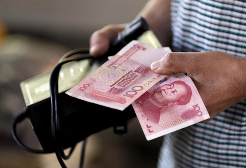 © Reuters. A customer holds a 100 Yuan note at a market in Beijing