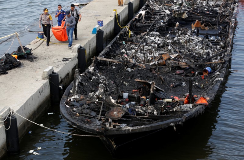 © Reuters. The remains of a victim is carried away after a fire ripped through a boat carrying tourists to islands north of the capital, at Muara Angke port in Jakarta