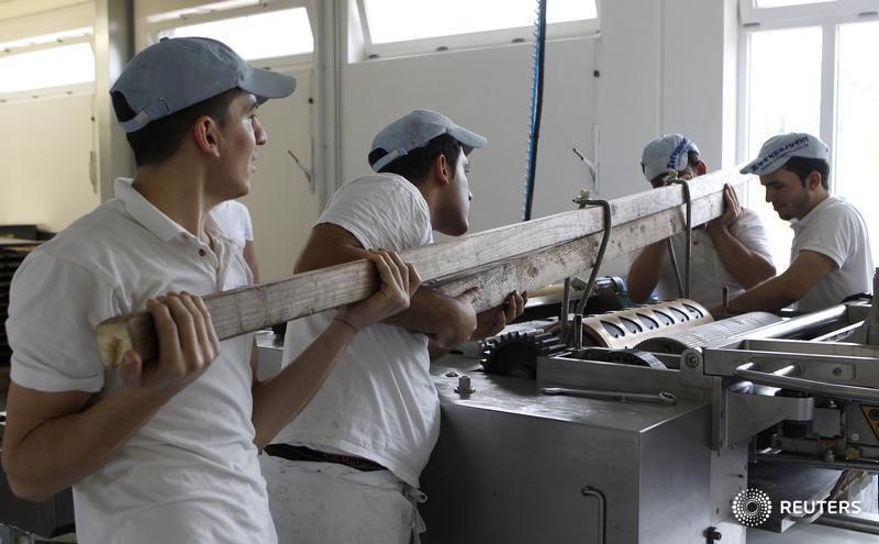 © Reuters. Workers fix in place a cookie cutter roll for small gingerbread Oktoberfest hearts at  Zuckersucht bakery in Aschheim