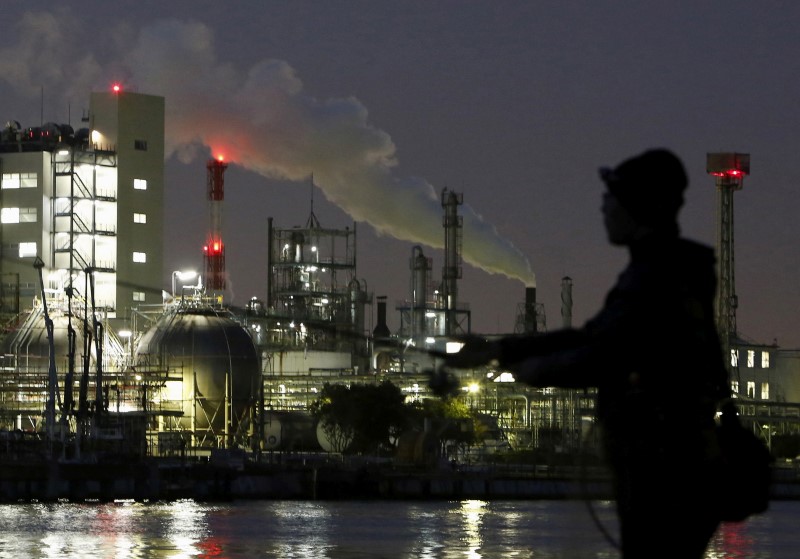 © Reuters. Smoke is emitted from a chimney as a man fishes at the Keihin industrial zone in Kawasaki