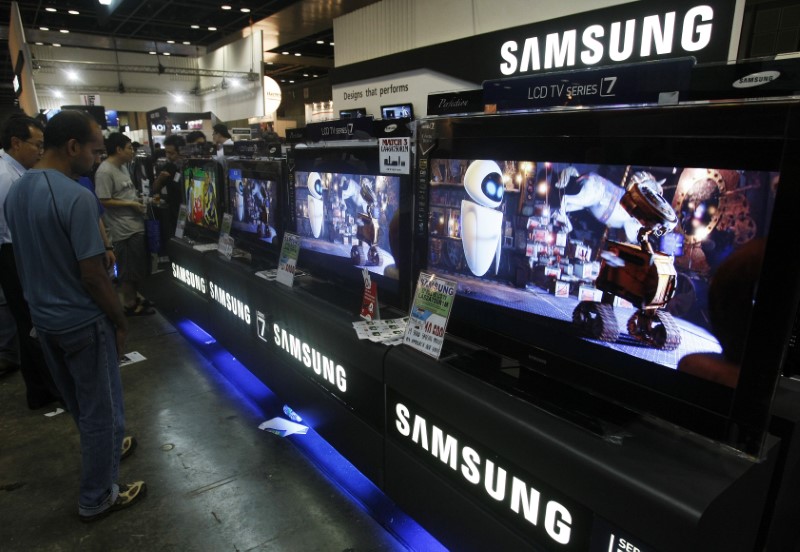 © Reuters. Man looks at a display of Samsung LCD and plasma televisions at during the I.T. show in Singapore