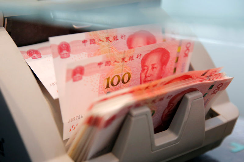 © Reuters. FILE PHOTO: Chinese 100 yuan banknotes are seen in a counting machine while a clerk counts them at a branch of a commercial bank in Beijing