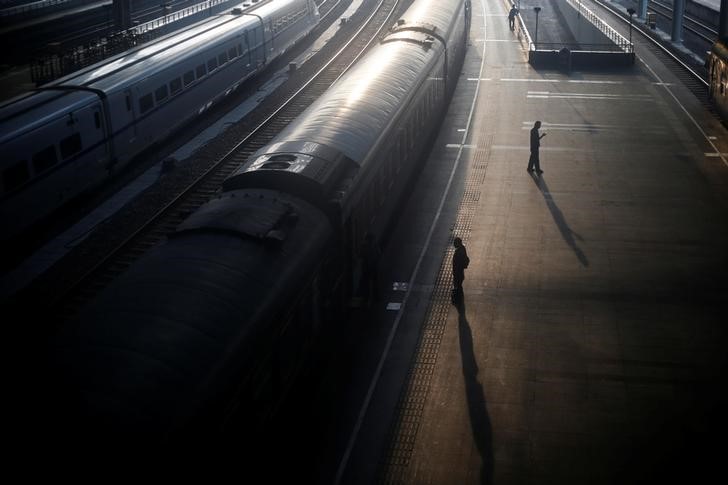 © Reuters. People stand next to a train at a railway station in Nanjing