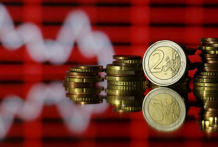 © Reuters. Euro coins are seen in front of a displayed stock graph in this photo illustration